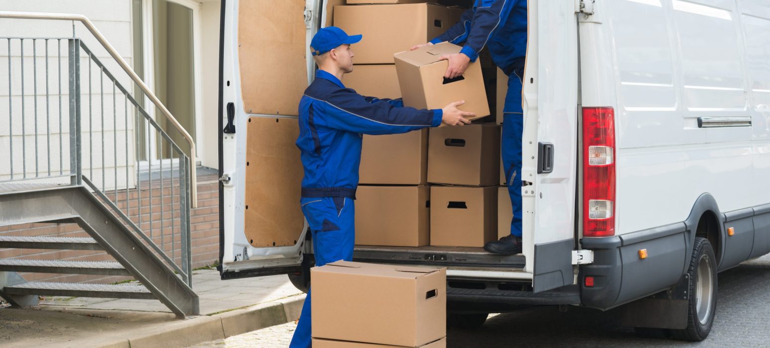 Young,Delivery,Men,Unloading,Cardboard,Boxes,From,Truck